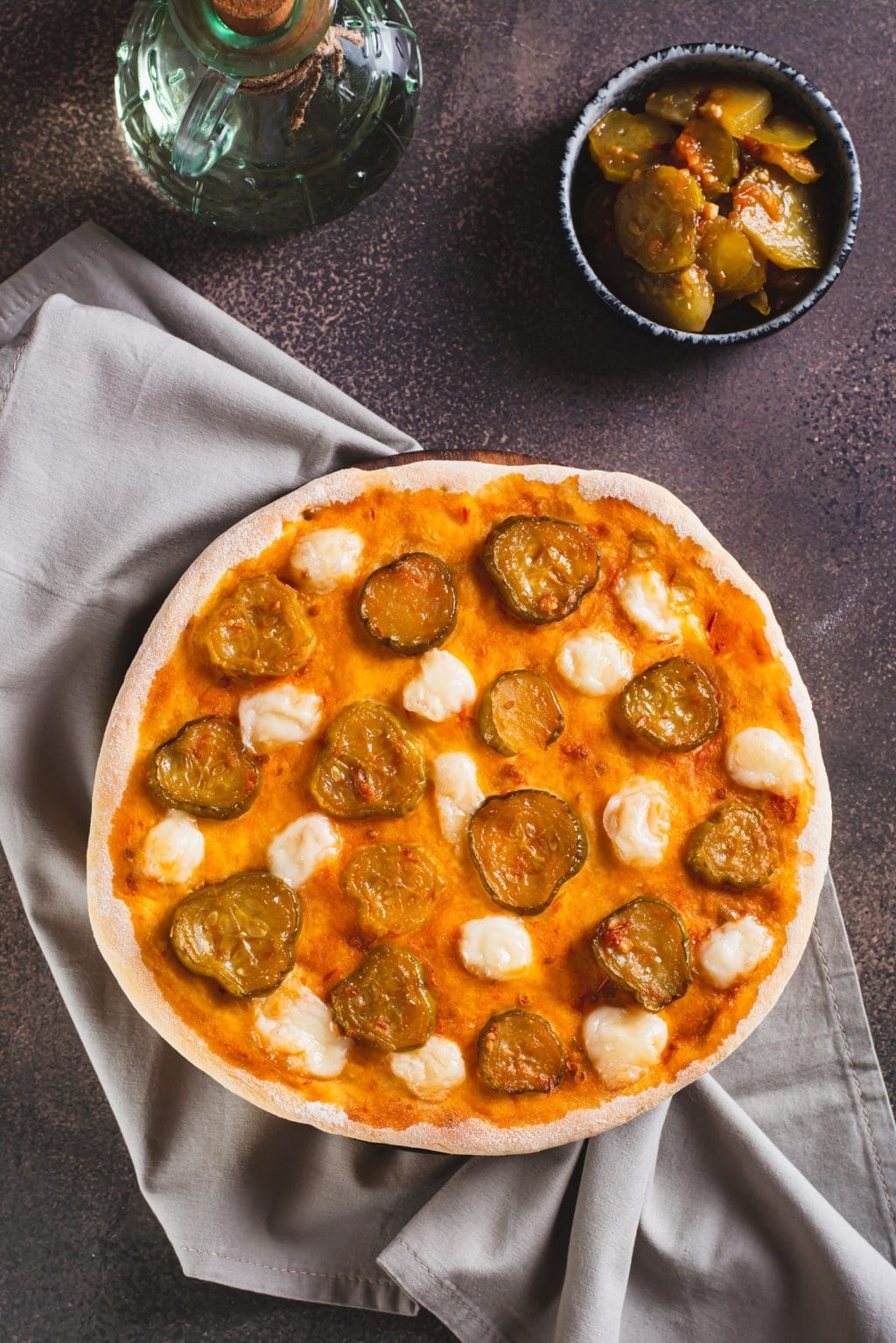 spicy pizza with cheese and pickles on a wooden board on the tab